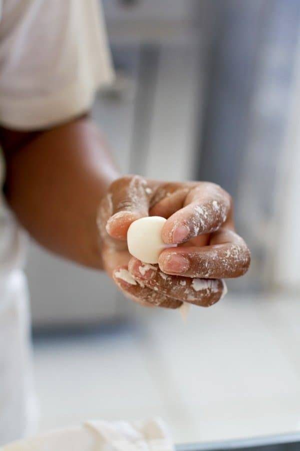 Hand holding a coconut and sugar coated Filipino palitaw.