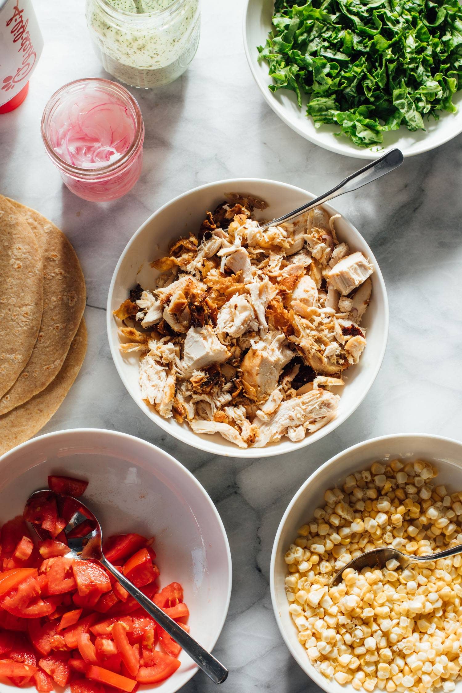 Chicken wrap assembly prep ready on a table in bowls.
