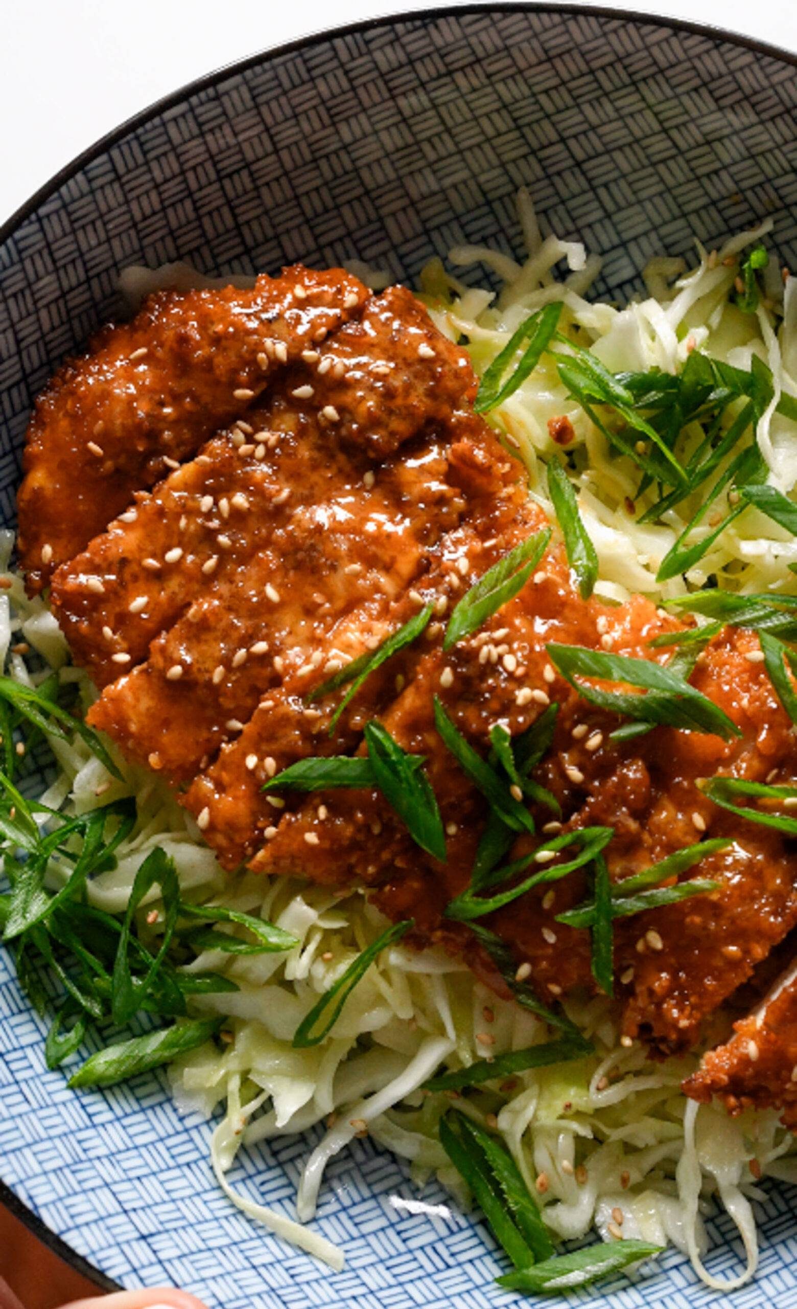 Gochujang chicken on a bowl of shredded cabbage.