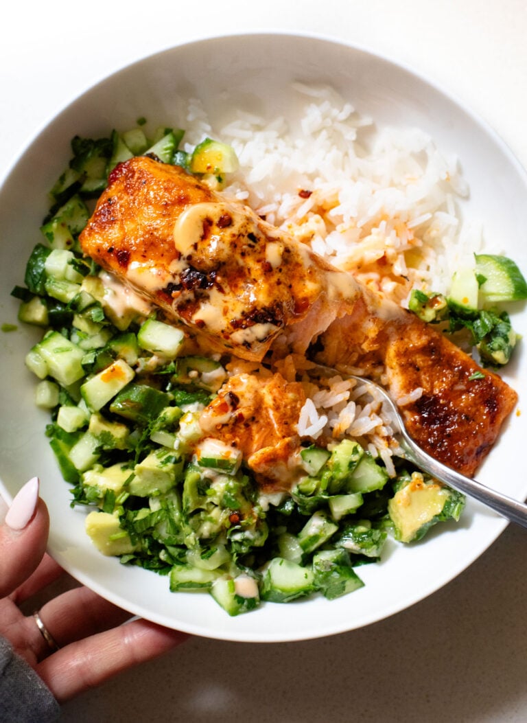 Salmon in a bowl with cucumber and rice.