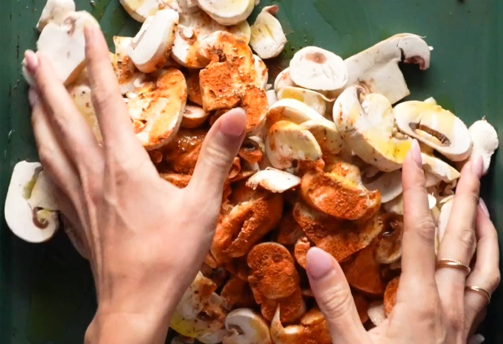 Tossing mushrooms with spices on a sheet pan.