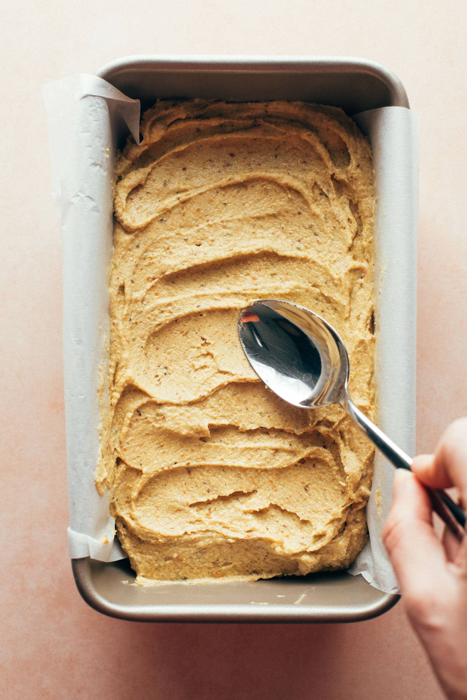 Spreading pistachio loaf batter in baking pan.