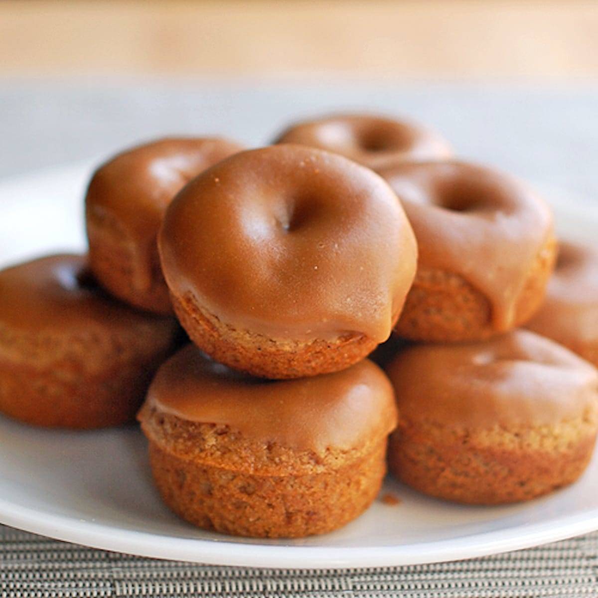 Baked Gingerbread Mini Donuts stacked on a plate.
